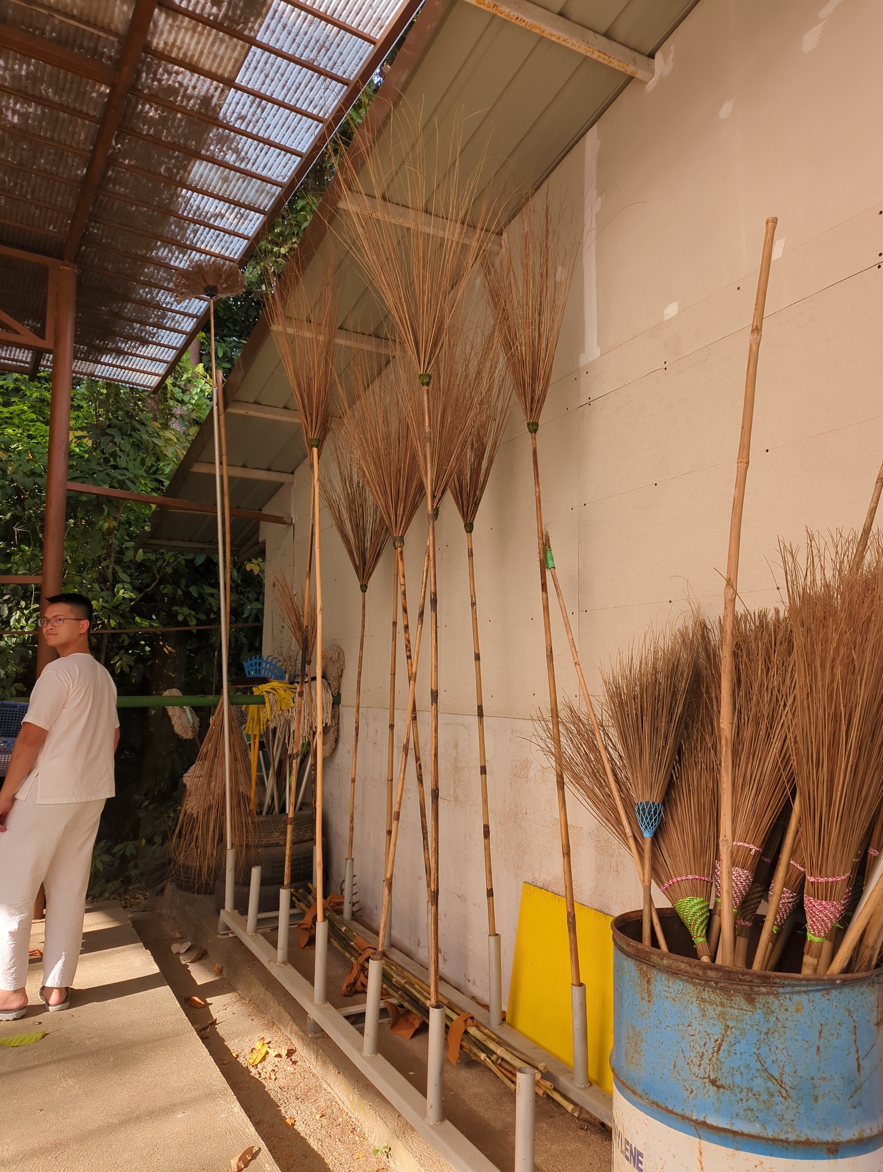 Brooms with Bear for scale. I wouldn’t be surprised if White Lotus made every one of the brooms you see here. Also notice the bundle of bamboo wrapped in orange rags on the ground. These were freshly flame-hardened broom handles. Soon the Broom CEO would take a dremel to the splintery bamboo joints to smooth them out before joining each handle to a homemade brush head.